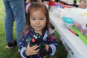 A young girl holds up her newly made ammonite sock 